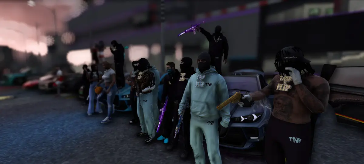 A DRILL UK crew in pale blue tracksuits and balaclavas lined up beside their cars at dusk, one stood on a car roof with a rifle raised