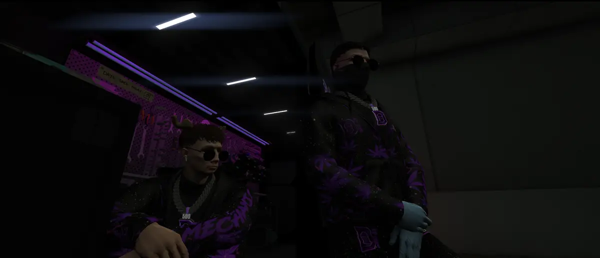 Two DRILL UK mechanics in purple patterned jackets and sunglasses sat in a dim garage under strip lights