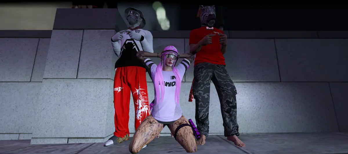 Three DRILL UK players posing against a wall at night, one kneeling in a pink and white outfit with the other two stood behind
